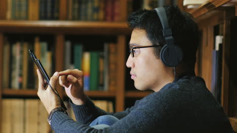 a young asian man with glasses using a tablet