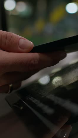 woman holding a phone and reading a book at night