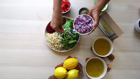 Hinzufügen-Von-Roten-Zwiebeln-Zu-Einem-Teller-Salat,-Hinzufügen-Von-Tomaten,-Karotten,-Spinat,-Kichererbsen,-Zitronen,-Zwiebeln,-Nüssen,-Dressing-Im-Blickfeld