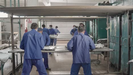 leather factory workers processing large sheets of leather