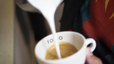 cerca de las manos del barista hacer café latte arte con máquina de café espresso en la cafetería