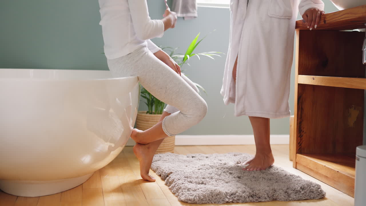 Mother and daughter brushing teeth in bathroom