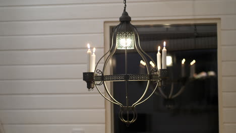 ornamental chandelier with four candles rotates slowly, reflects in window