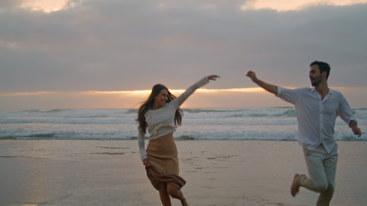 pareja de amor corriendo juntos al atardecer en la playa del océano. amantes étnicos disfrutando en una cita