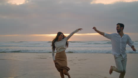 love couple running ocean beach sunset together. ethnic lovers enjoying on date