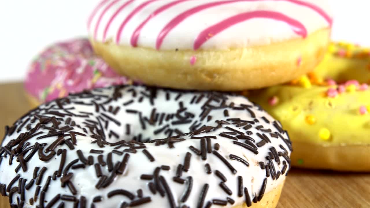 rosquillas giratorias con diferentes rellenos en la mesa. deliciosa rosquilla dulce girando en un plato. rosquilla brillante y colorida macro disparo de primer plano girando sobre un fondo blanco. bucle sin costuras.