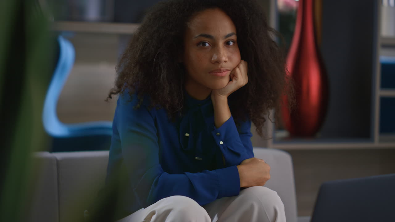 Focused african american business woman looking camera sitting in workplace.