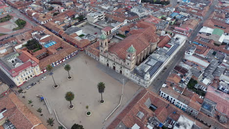 drone footage captures zipaquira’s main plaza with its historic cathedral, surrounded by a vibrant array of densely packed rooftops under soft, diffused lighting, offering a panoramic cityscape