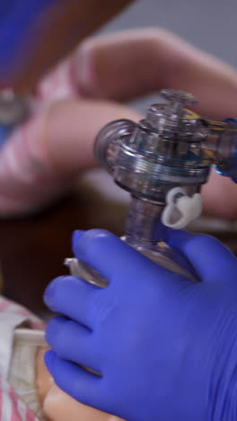 breathing session on a doll. hands in medical gloves doing chest compression on a baby mannequin. training cpr procedure in rescue center. close-up. vertical video
