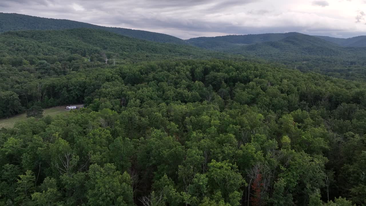 Aerial panorama of forest landscape and hills under grey dark cloudy sky in USA. Wide shot. Blue ridge mountains of Virginia in distance