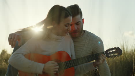 couple playing guitar at sunset during valentine's travel