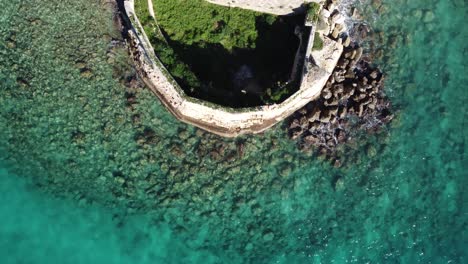 aerial top down revealing castle ruins on little island of souda bay, crete greece