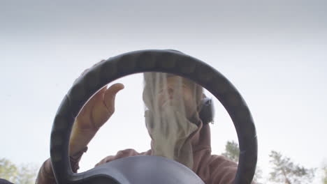 man with mosquito head net on riding mower annoyed by pestering mosquitoes, pov