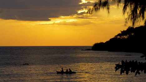 silueta de personas en un kayak en el océano al atardecer