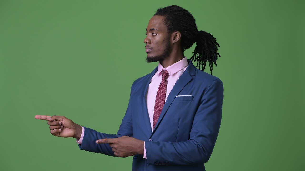 Young handsome African businessman with dreadlocks against green background