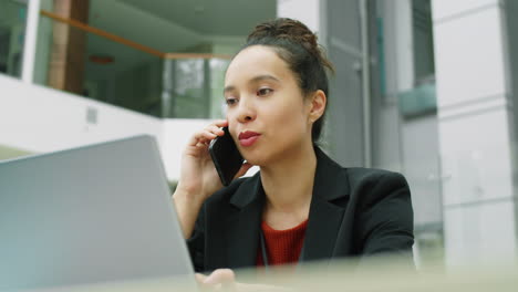 mujer de negocios usando computadora portátil y hablando por teléfono en el centro de la oficina