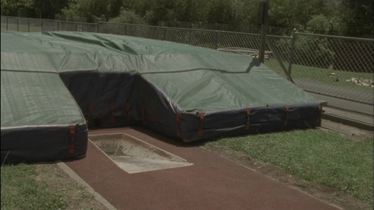 한 젊은이가 장대높이뛰기를 실행하고 매트에 착지합니다.