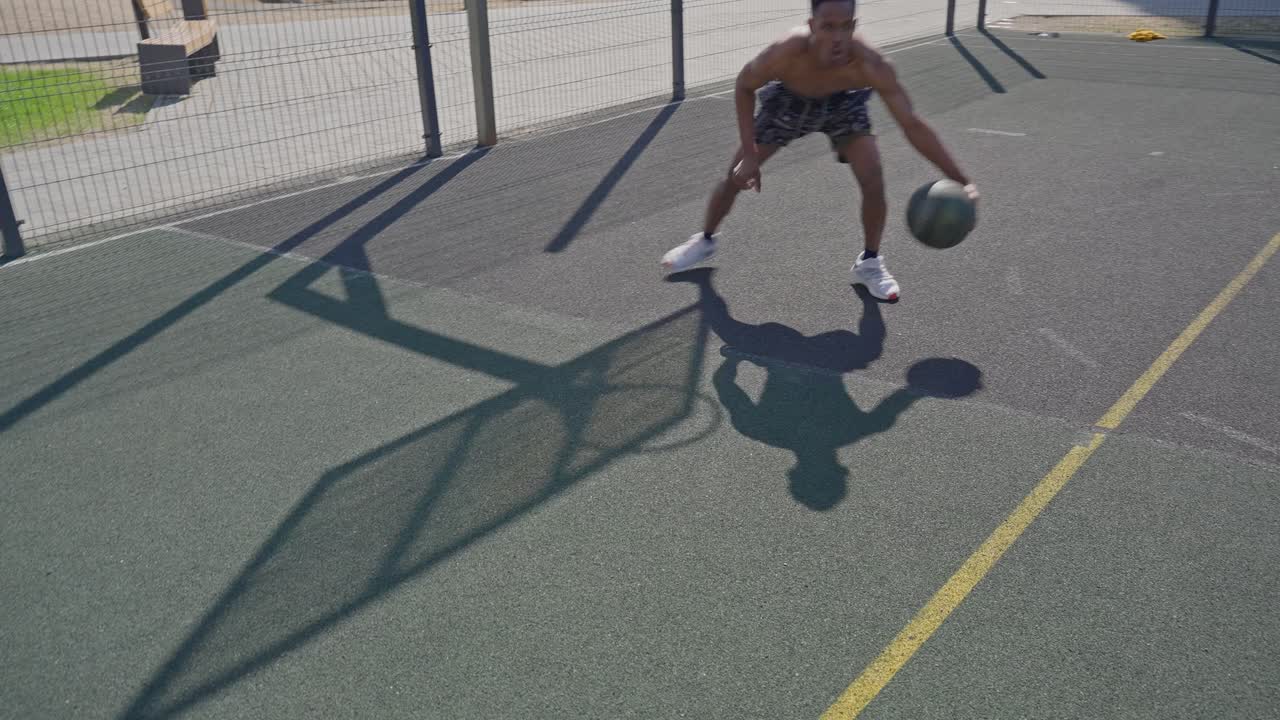 Giovane uomo che palleggia a basket su un campo all'aperto