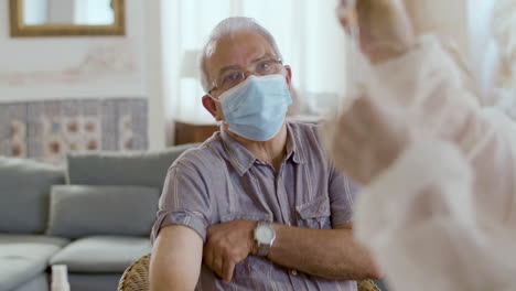 Front-view-of-serious-old-man-rolling-up-sleeve-for-vaccination