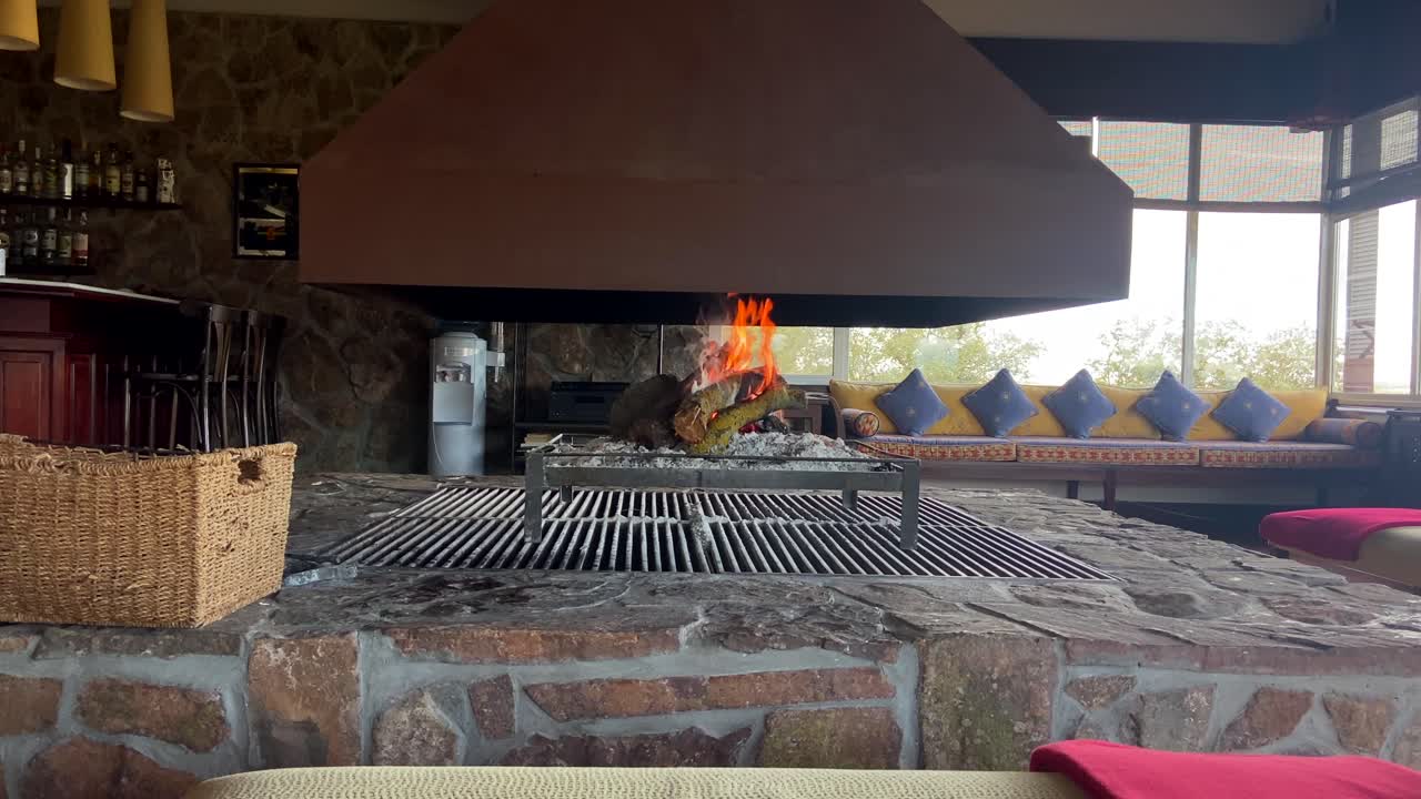 imágenes estáticas de 4k de un salón de hotel perfectamente decorado con una gran chimenea ardiendo en el centro en un día lluvioso