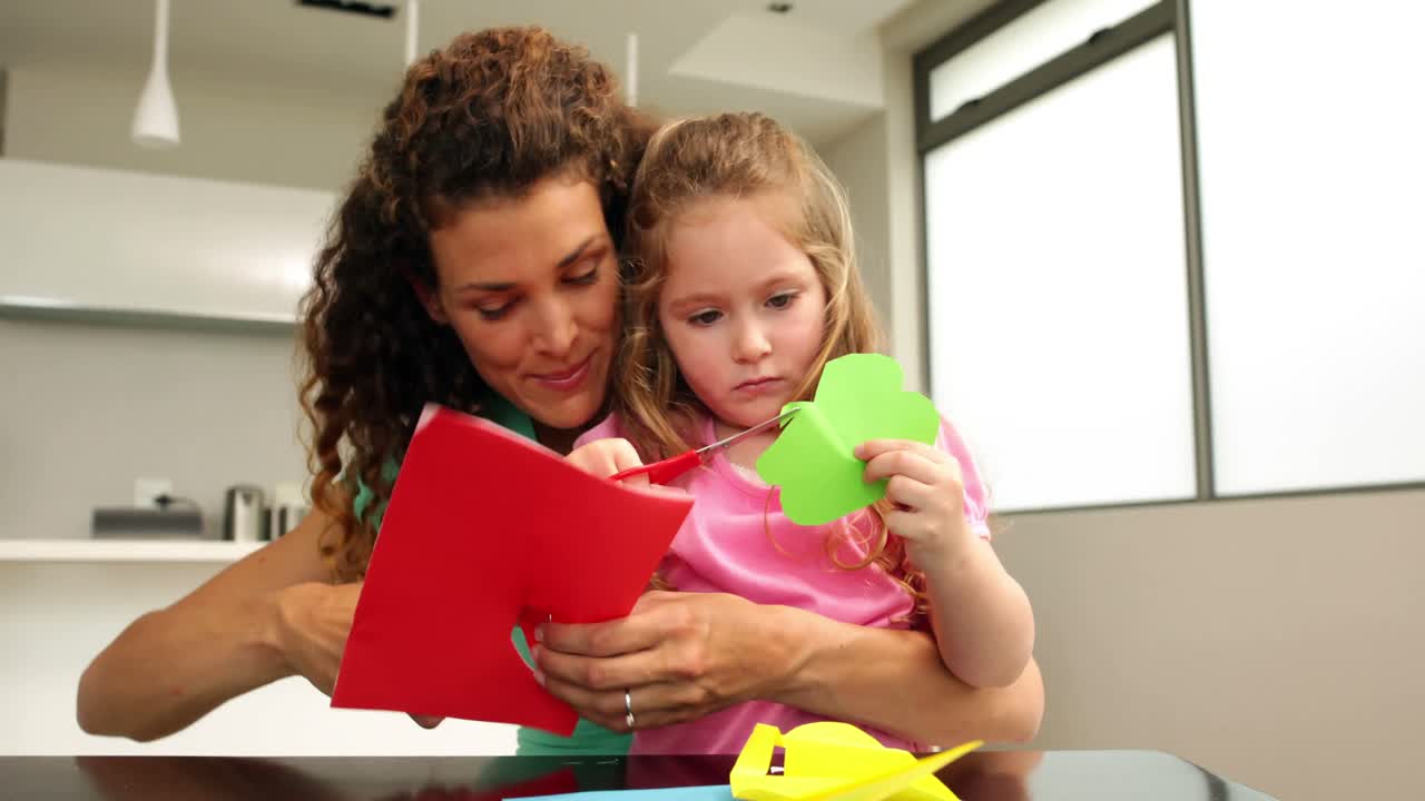 madre y hija lindas haciendo artes y artesanías en la mesa de la cocina