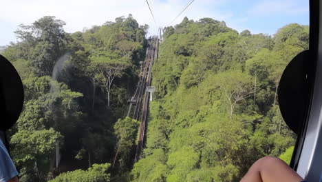 scenic cable car view ascending a steep forested mountain