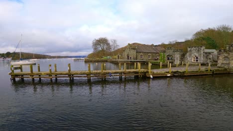 lake windermere in the english lake district, with its iconic wooden jetty, historic stone-built buildings, and moody grey skies