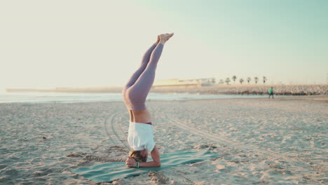 Yogi-Mädchen-Macht-Kopfstand-Und-übt-Yoga-Posen-Am-Meer.