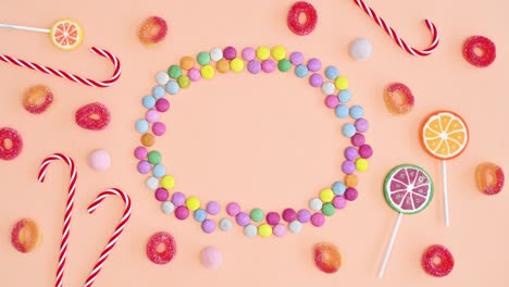 candies and lollipops make creative frame copy space on bright pastel orange background. stop motion flat lay