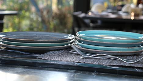 una pila de platos limpios y platos de plata en una mesa en un restaurante
