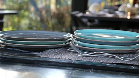 a stack of clean plates and silverware set on a table in a restaurant