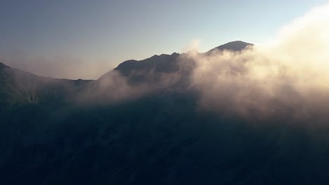 lifting shot up and over the mountain range flying through the clouds