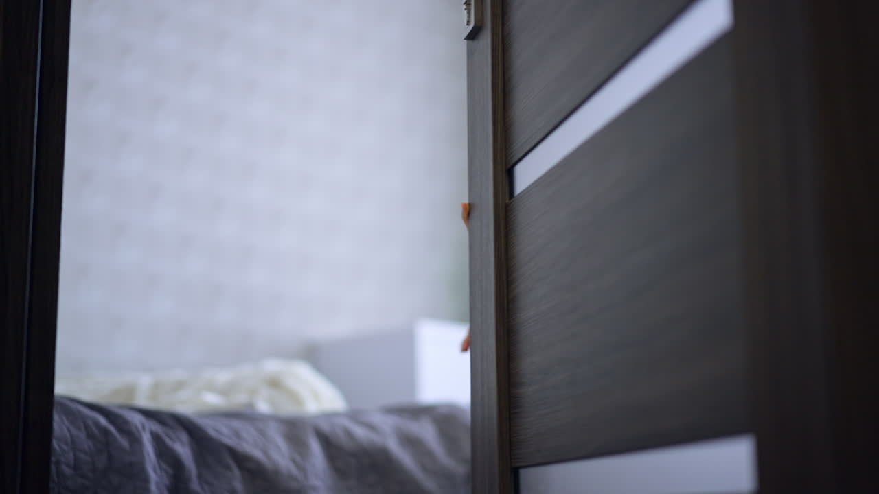 Caucasian child closes the door to a bedroom slowly. Calm baby boy playing at home.