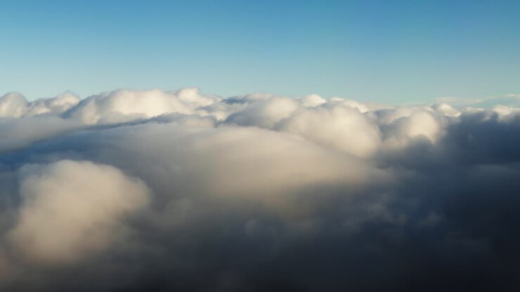 Aerial view of soft white clouds from high altitude. Calm atmospheric scene above cloud layer during flight