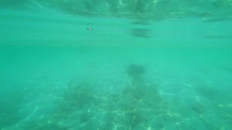 Tauchen-Sie-Ein-In-Wunderschönes-Türkisfarbenes-Wasser-Mit-Reflexionen-Und-Licht-Auf-Der-Oberfläche-Und-Dem-Strand-In-Der-Ferne