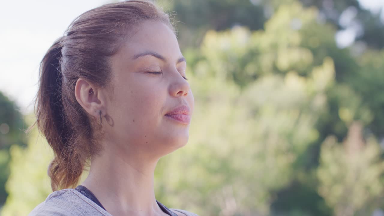 Mulher afro-americana meditando à esquerda no parque, com as palmas das mãos juntas, respirando, com espaço para texto.