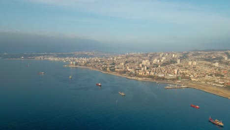 aerial dolly in of valparaiso picturesque hillside city and cargo ships sailing in sea near the coastline, chile