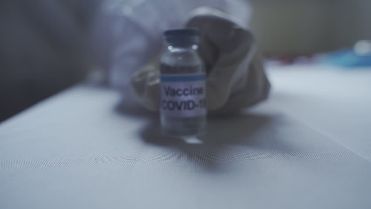 mano de un trabajador médico acercándose lentamente a la cámara mientras revela la vacuna covid 19