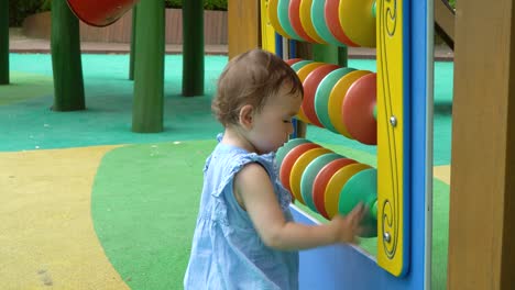 2 years old ukrainian-korean cute toddler girl learning and having fun spinning colorful disks at playground, korean-ukrainian multi-ethnic baby girl