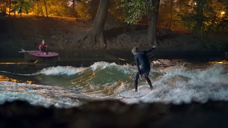 Cinematográfico-Desvanecerse-En-Cámara-Lenta-Eisbach-Ola-Río-Surfista-Comunidad-Munich-Alemania-Nivel-Del-Suelo-Caer-Otoño-Hermosa-Noche-Surf-Alto-Flujo-Agua-Navegar-Alta-Baviera-Alpes-Fluir-Seguir-Movimiento