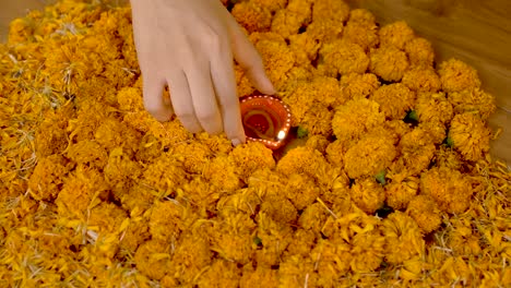 indian woman putting diya in center of rangoli