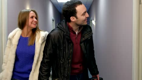 happy young couple with suitcase looking for their hotel room