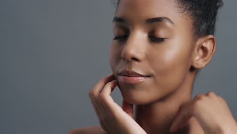 Primer-Plano-Retrato-Hermosa-Mujer-Afroamericana-Tocando-Suavemente-La-Cara-Con-Las-Manos-Disfrutando-De-Una-Tez-De-Piel-Suave-Y-Saludable-Concepto-De-Cuidado-De-La-Piel-De-Belleza-Femenina-Natural