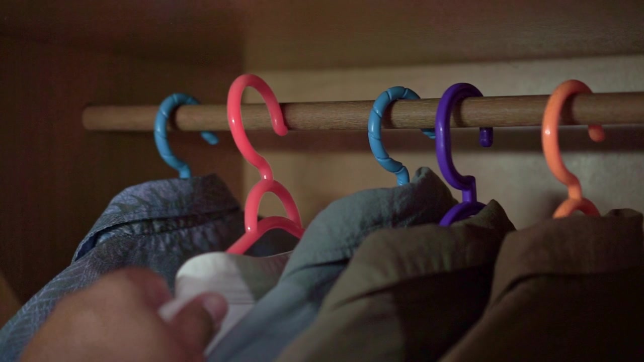 Hand returning a clothes hanger into a wardrobe. Perfect for home organization, clothing storage, closet management, and everyday household routine concepts.