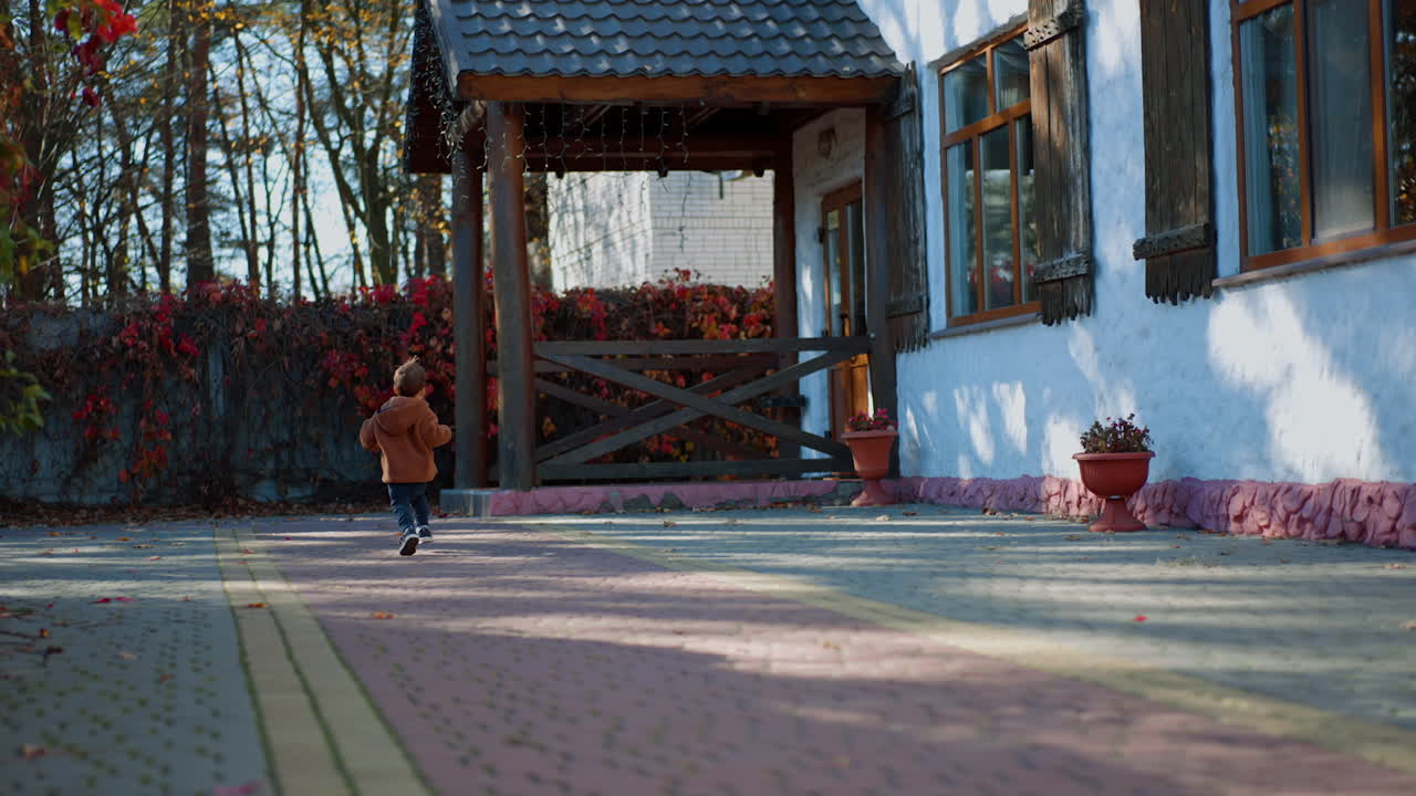 Rear view of a little toddler running outdoors. Happy energetic baby having active time in autumn.