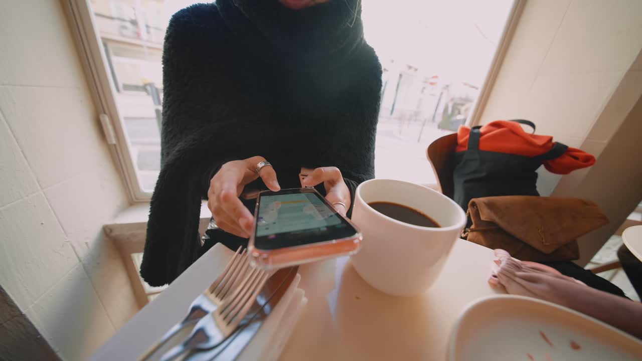 A person using a phone at a cafe with coffee