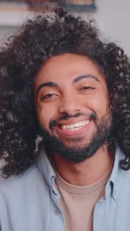joyful man with curly hair smiles warmly in a cozy indoor setting