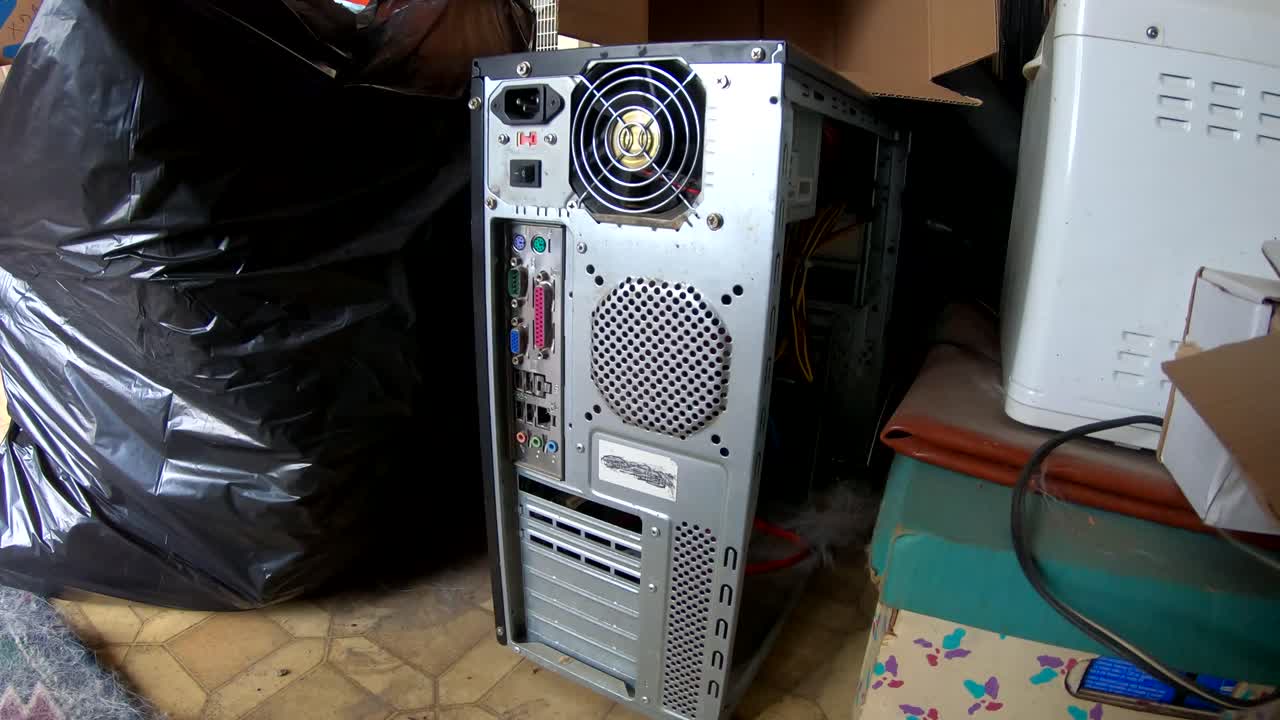 Old computer tower sitting next to garbage in a old home.
