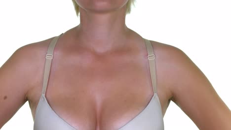 a close-up of a woman's chest readjusting her bra straps, on a seamless white studio background