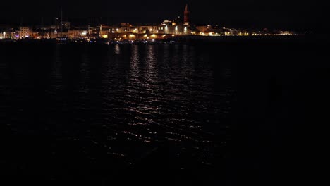 tilt up motion panoramic view of city centre of alghero port at night